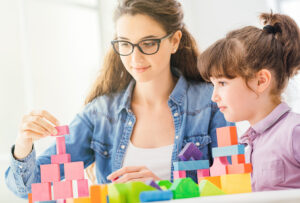 Nanny playing bricks with girl